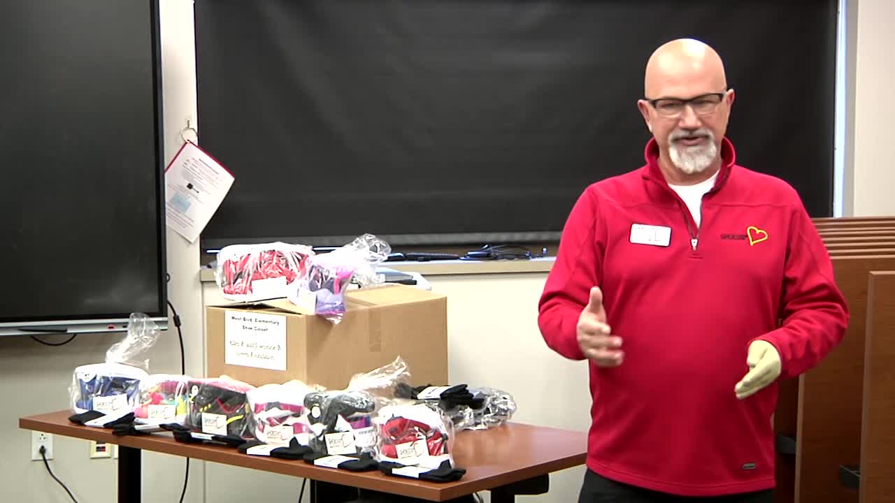 Gentleman explains the Shoes From the Heart program next to a box of new shoes.