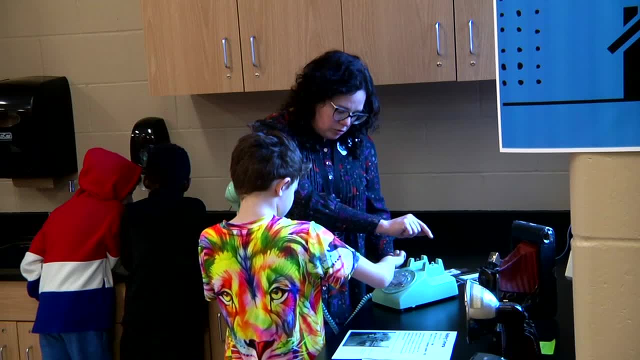 Media Specialist shows a Beulah Ralph Elementary student how to use a rotary telephone.
