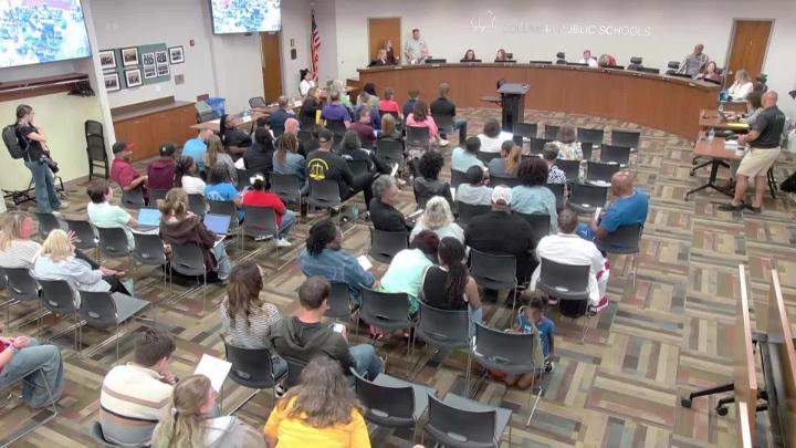 School board room filled with people seated facing the dais.
